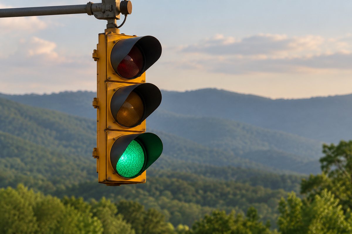 Green traffic signal against distant wooded hills